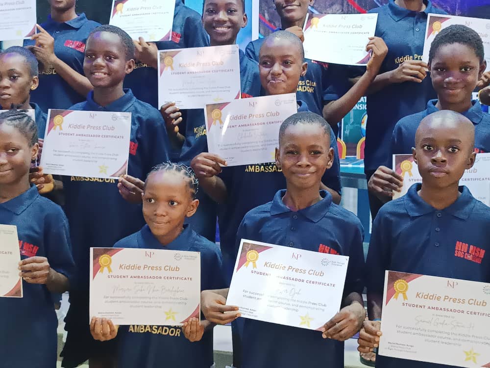 Students holding their Kiddie Press Club certificates